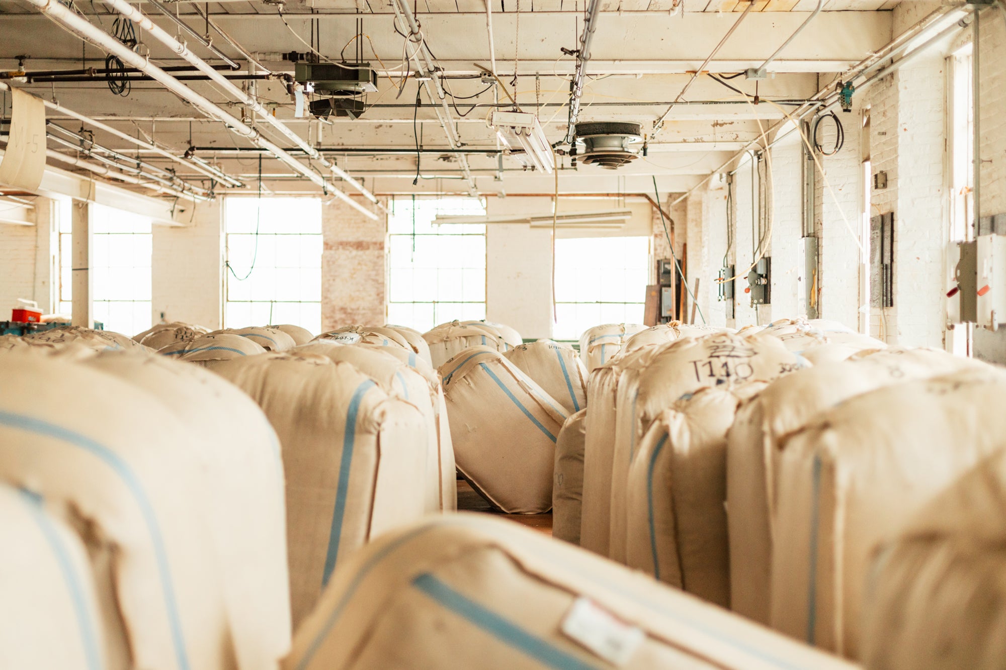 Bales of wool in brightly light factory room.