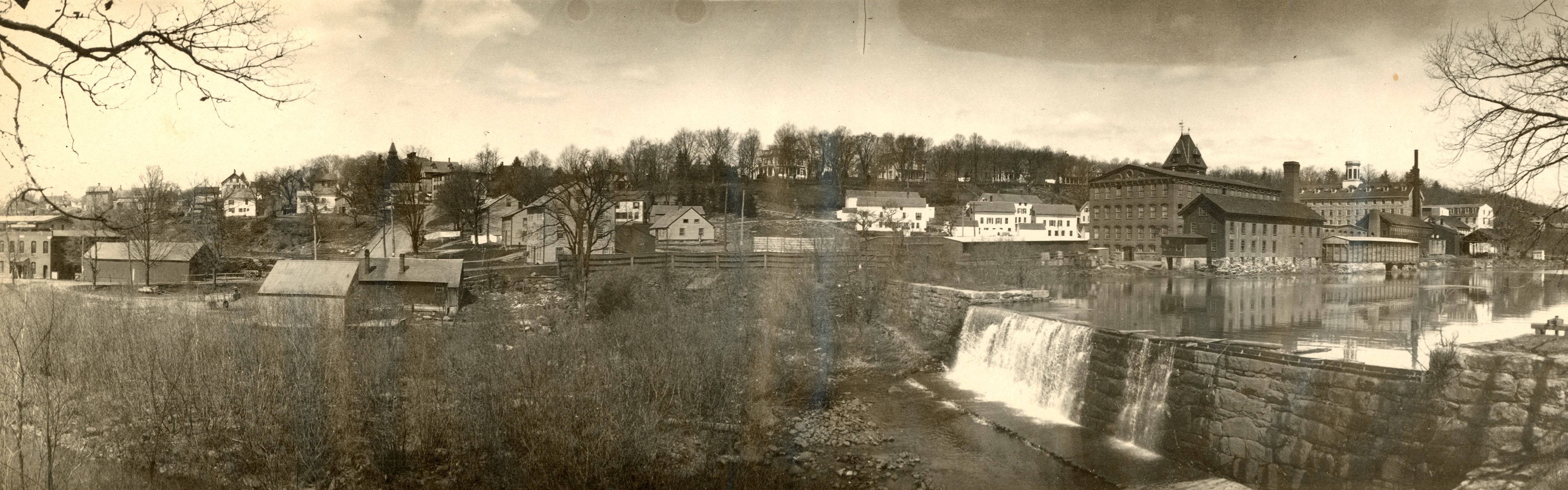 Historical photo of old mill buildings near a river and falls. 